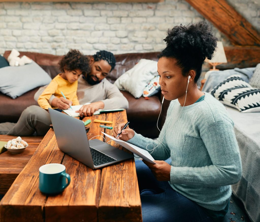 African American mother has conference call while working on laptop at home.